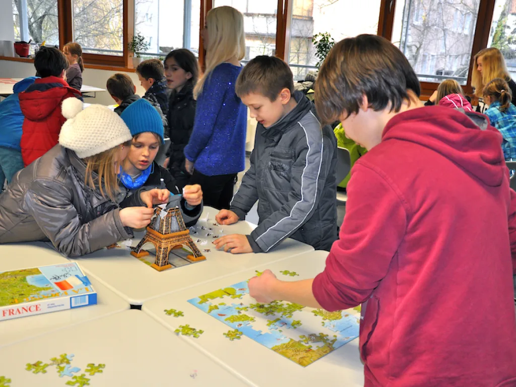 Kinder spielen an einem Tisch ein Landkartenspiel.